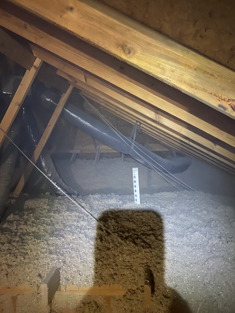 Fresh blown-in insulation measured with a depth ruler