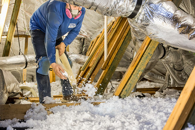 Installer blowing in insulation in an attic